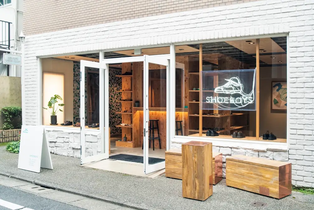 シューズショップの外観。白いレンガ壁と木のベンチ