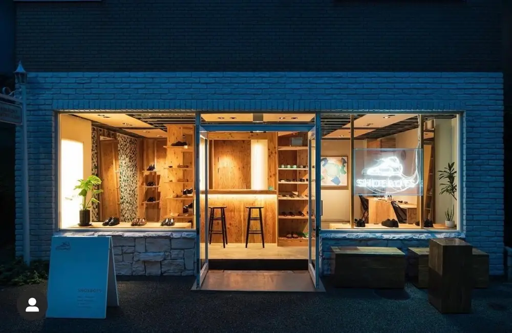 シューズショップの夜の外観。店内の照明が通りに広がる